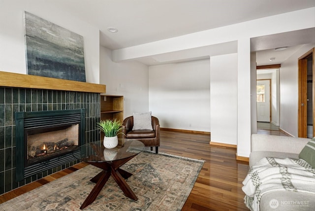 living area featuring a fireplace, baseboards, and wood finished floors