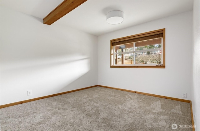 unfurnished room featuring carpet floors, beam ceiling, and baseboards