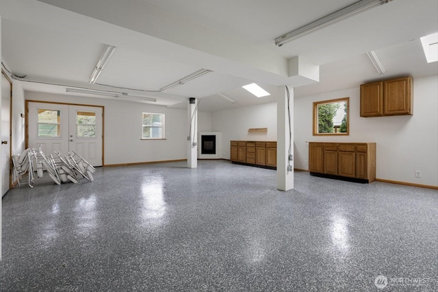 below grade area featuring a wealth of natural light, a glass covered fireplace, and baseboards