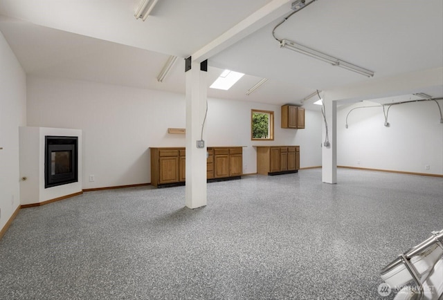 basement with a glass covered fireplace and baseboards