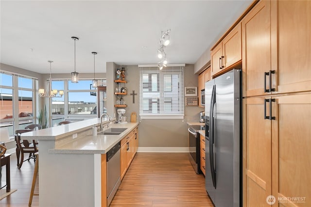 kitchen featuring appliances with stainless steel finishes, light wood-type flooring, a breakfast bar, sink, and kitchen peninsula