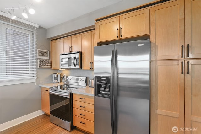 kitchen with rail lighting, stainless steel appliances, and light hardwood / wood-style floors