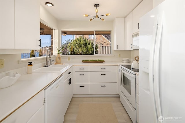 kitchen with sink, white cabinetry, a chandelier, hanging light fixtures, and white appliances