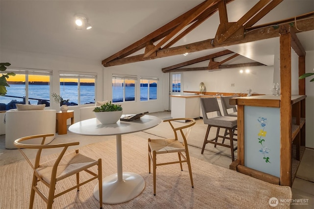 dining area with vaulted ceiling with beams and a water view