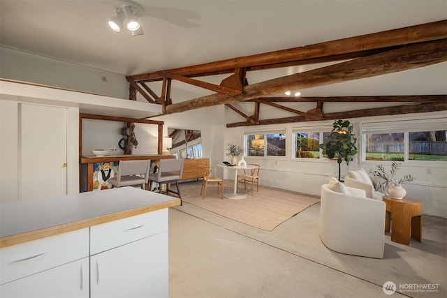 interior space with ceiling fan and vaulted ceiling with beams