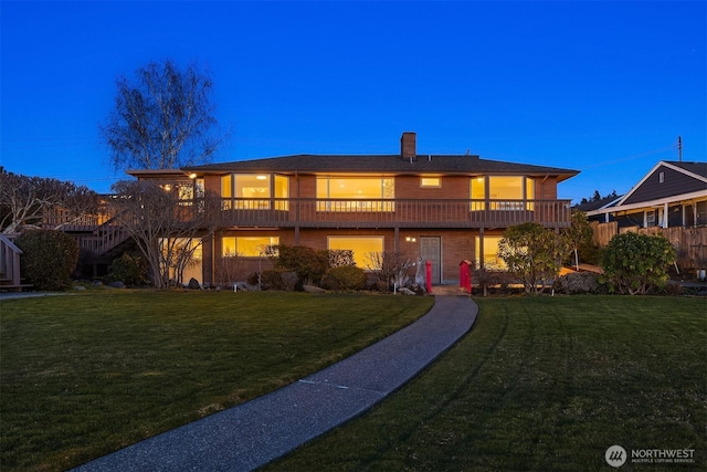 back house at dusk featuring a lawn