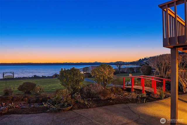 yard at dusk featuring a water view