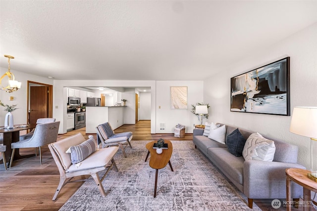 living room with wood-type flooring, a textured ceiling, and a notable chandelier