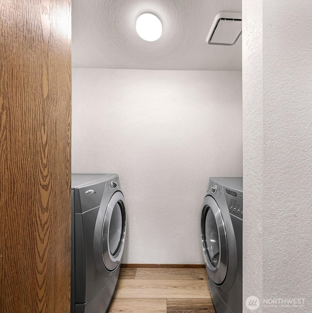 laundry area with washer and clothes dryer, a textured ceiling, and light wood-type flooring