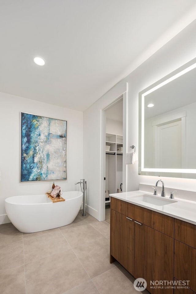 bathroom with a freestanding bath, tile patterned flooring, vanity, and recessed lighting