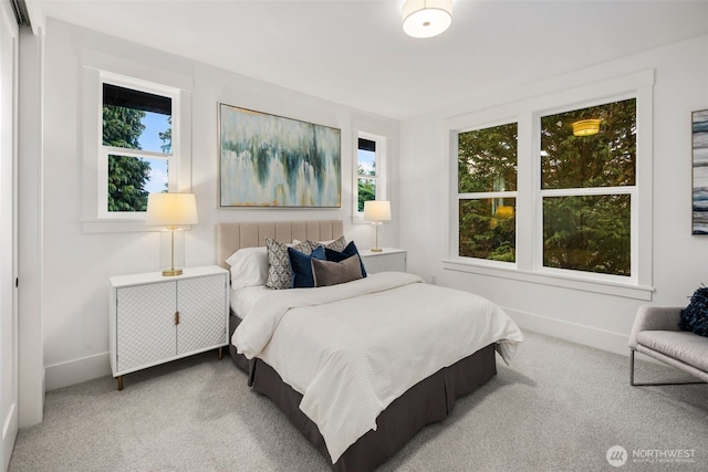 carpeted bedroom featuring multiple windows and baseboards