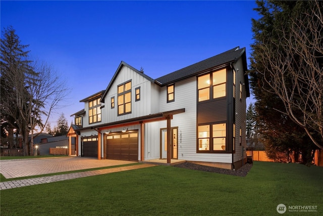 modern inspired farmhouse featuring a garage, fence, a yard, decorative driveway, and board and batten siding