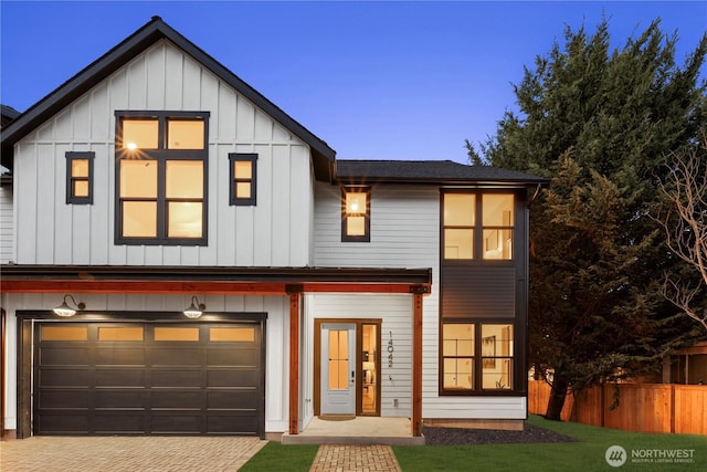 modern farmhouse with board and batten siding, decorative driveway, and fence