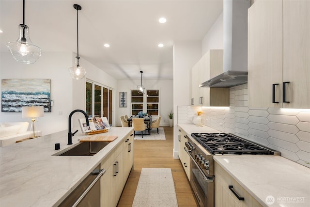 kitchen with a sink, light stone countertops, stainless steel appliances, wall chimney range hood, and backsplash