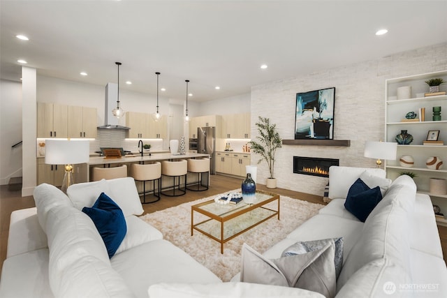 living area with a stone fireplace, recessed lighting, and light wood-style floors