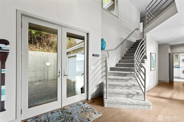 doorway with baseboards, light wood-style floors, stairs, french doors, and stacked washing maching and dryer