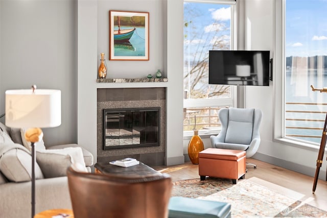 living room featuring light wood-type flooring, baseboards, and a tiled fireplace