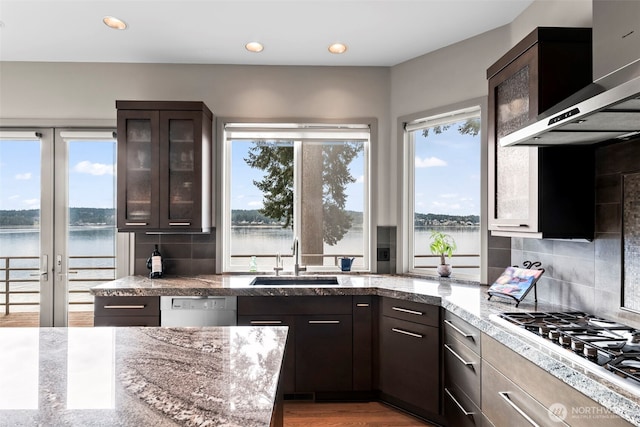 kitchen featuring dark brown cabinets, a water view, a sink, and glass insert cabinets