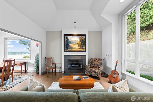 living room with lofted ceiling, baseboards, a tiled fireplace, and wood finished floors