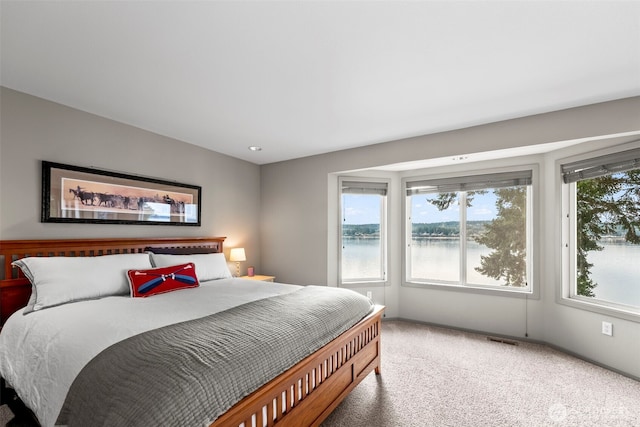 carpeted bedroom with a water view and visible vents