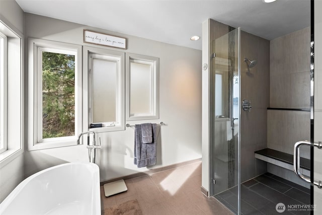 bathroom with baseboards, a soaking tub, a shower stall, and a healthy amount of sunlight