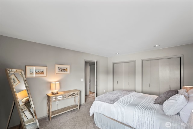 bedroom with light carpet, baseboards, and multiple closets