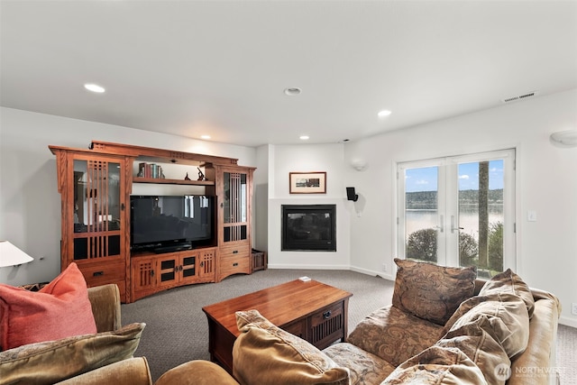 living area with visible vents, a glass covered fireplace, carpet, french doors, and recessed lighting