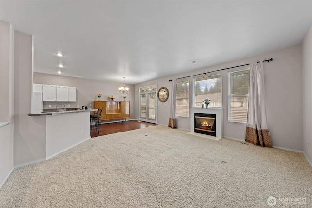 unfurnished living room featuring a chandelier, a fireplace with flush hearth, dark carpet, and recessed lighting