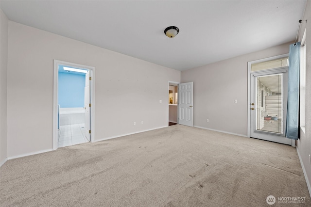 unfurnished bedroom with baseboards, ensuite bathroom, and carpet flooring