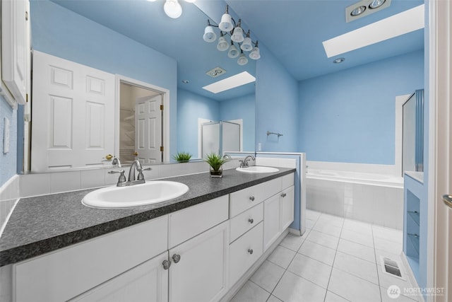 full bath with tile patterned flooring, a skylight, and a sink