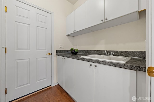 kitchen with white cabinetry, dark countertops, dark wood-type flooring, and a sink