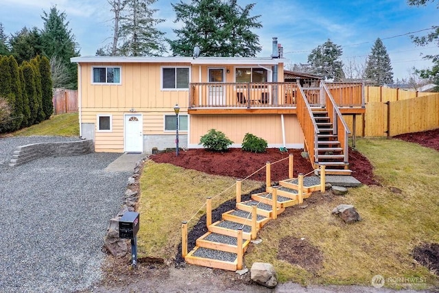 view of front of property featuring gravel driveway, fence, stairway, and board and batten siding