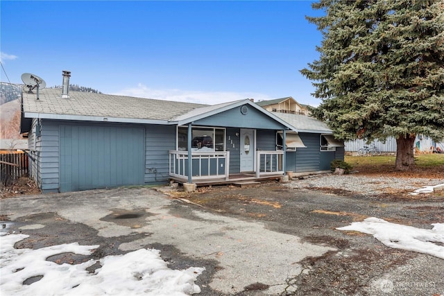 ranch-style home featuring aphalt driveway, covered porch, and a garage