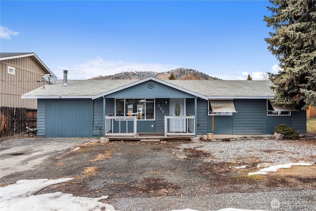 ranch-style home with driveway, covered porch, an attached garage, and fence