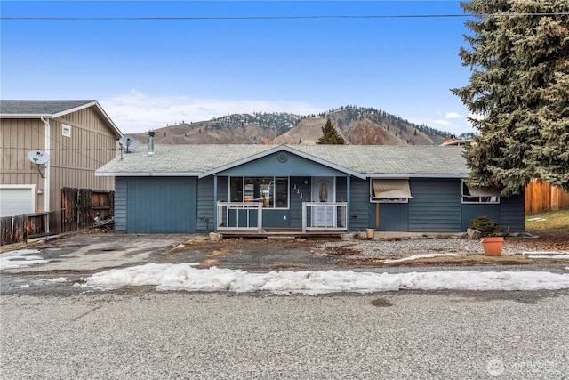 single story home featuring a porch, fence, driveway, and a mountain view