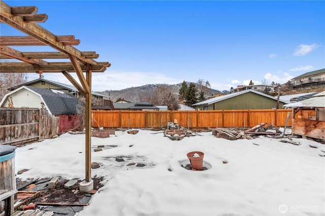 yard covered in snow with a fenced backyard and a pergola