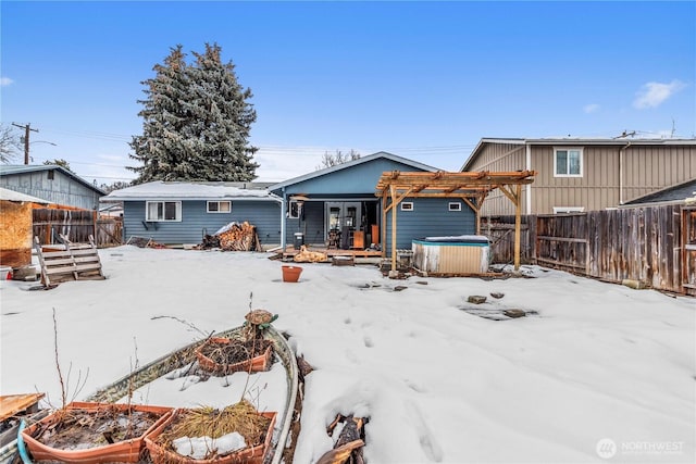 snow covered property featuring fence, a hot tub, and a pergola