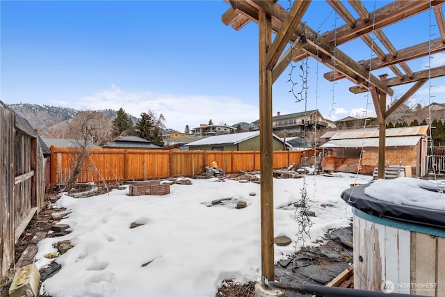 snowy yard with a fenced backyard and a pergola