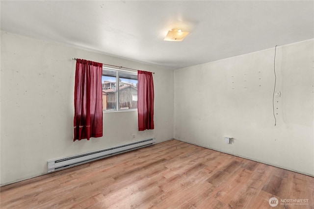 spare room featuring a baseboard heating unit and wood finished floors