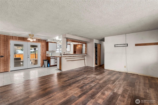 unfurnished living room featuring a textured ceiling, french doors, and wood finished floors