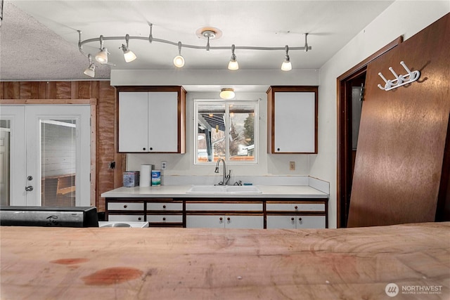 kitchen featuring white cabinetry, light countertops, a sink, and french doors