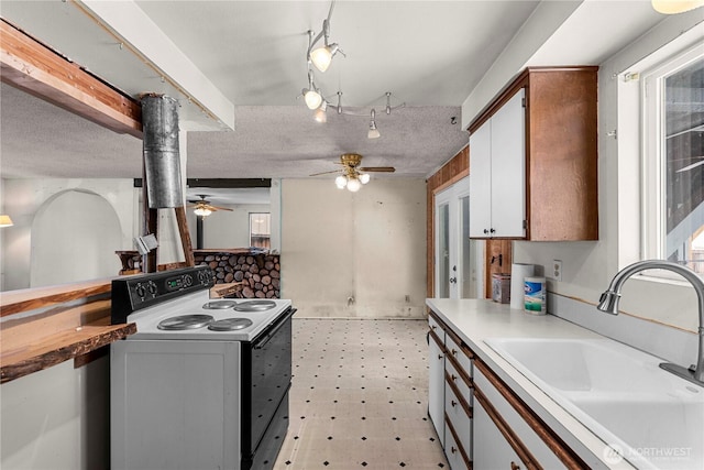 kitchen with electric range oven, light floors, a textured ceiling, and a sink