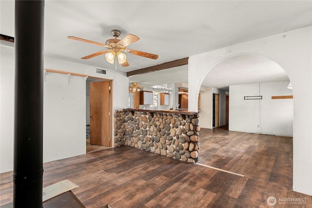 interior space with ceiling fan, visible vents, arched walkways, and wood finished floors