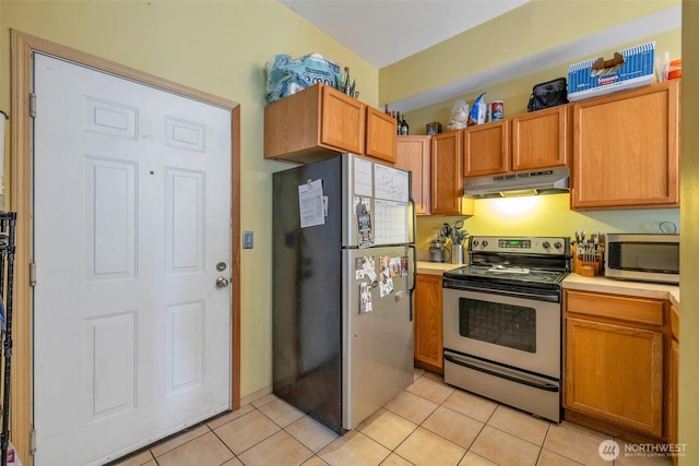 kitchen with light tile patterned floors, light countertops, appliances with stainless steel finishes, and under cabinet range hood