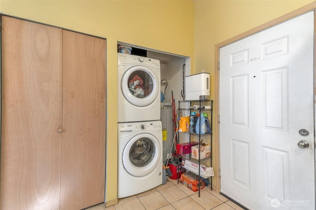 washroom featuring light tile patterned floors, stacked washer and dryer, and laundry area