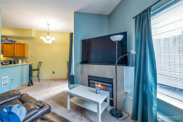 carpeted living room with a tile fireplace, visible vents, baseboards, and an inviting chandelier