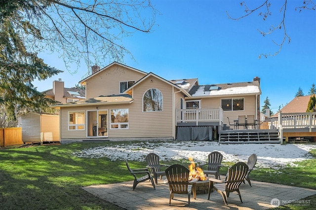 snow covered property featuring a yard, a deck, a patio, and an outdoor fire pit