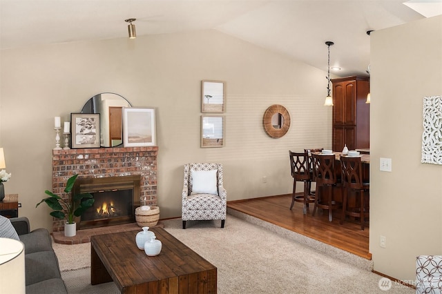 living room with a brick fireplace, vaulted ceiling, and light colored carpet