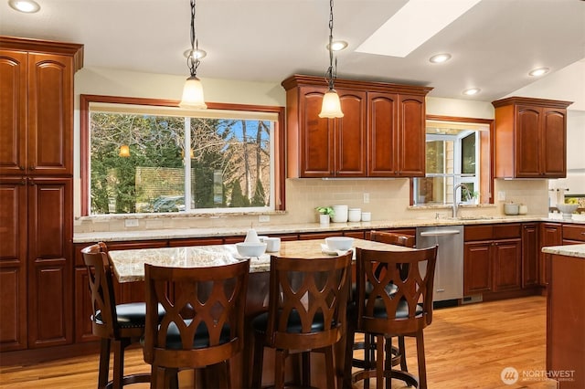 kitchen featuring hanging light fixtures, dishwasher, sink, and a kitchen breakfast bar