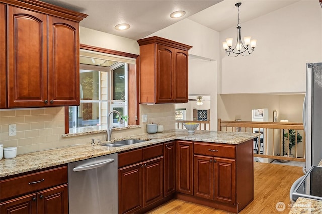 kitchen featuring sink, hanging light fixtures, stainless steel appliances, kitchen peninsula, and light wood-type flooring